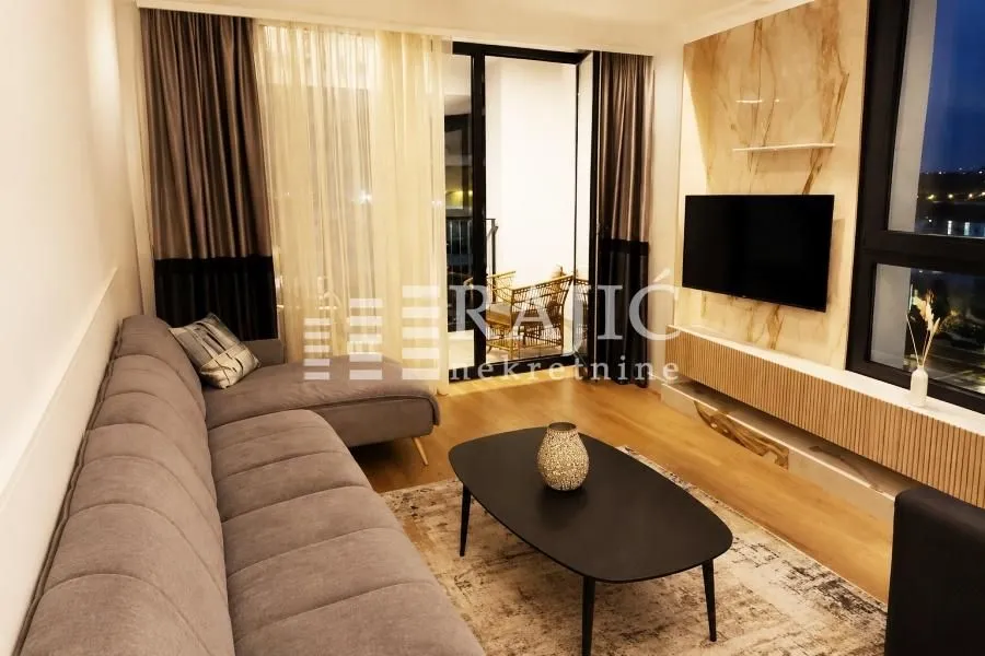 Modern living room with a sofa, TV, and access to the terrace.
