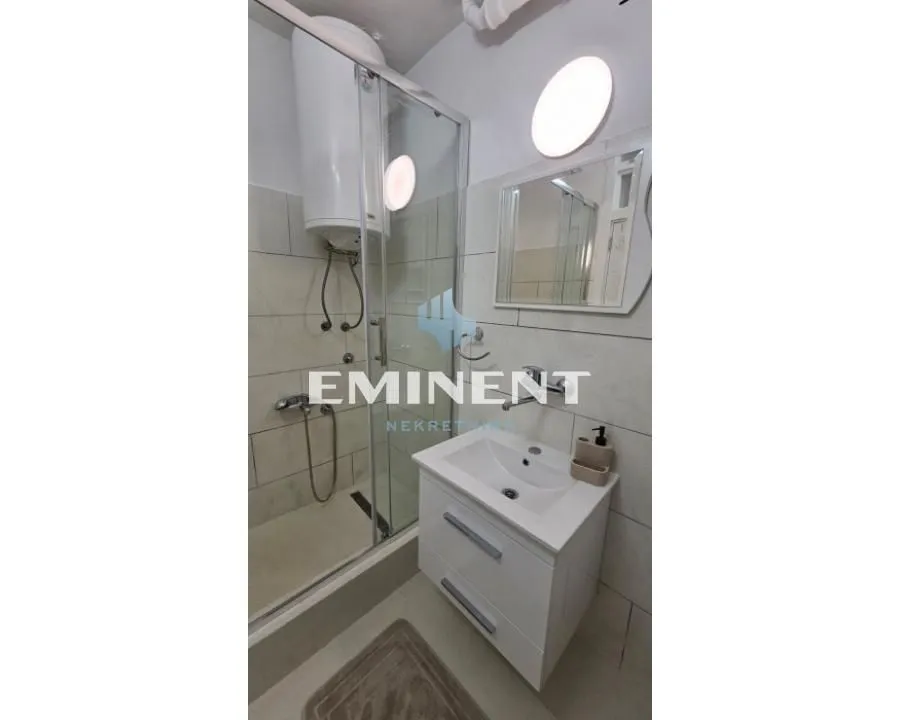 Smaller bathroom with a shower cabin, washbasin, and mirror.