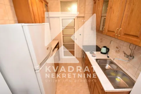 Small kitchen with wooden cabinetry, sink, and refrigerator. - image 5