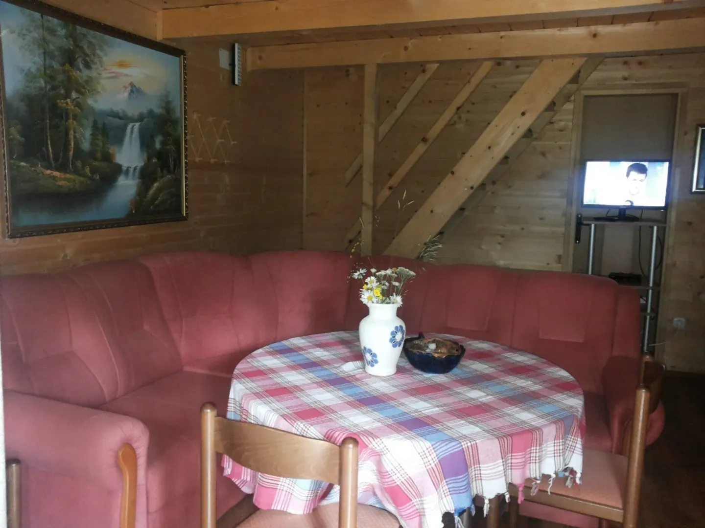 Dnevna soba u drvenoj kući sa garniturom i stolom.