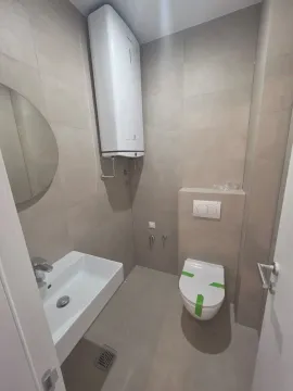 Manje kupatilo sa pločicama u neutralnim tonovima, umivaonikom i wc šoljom. - image 7