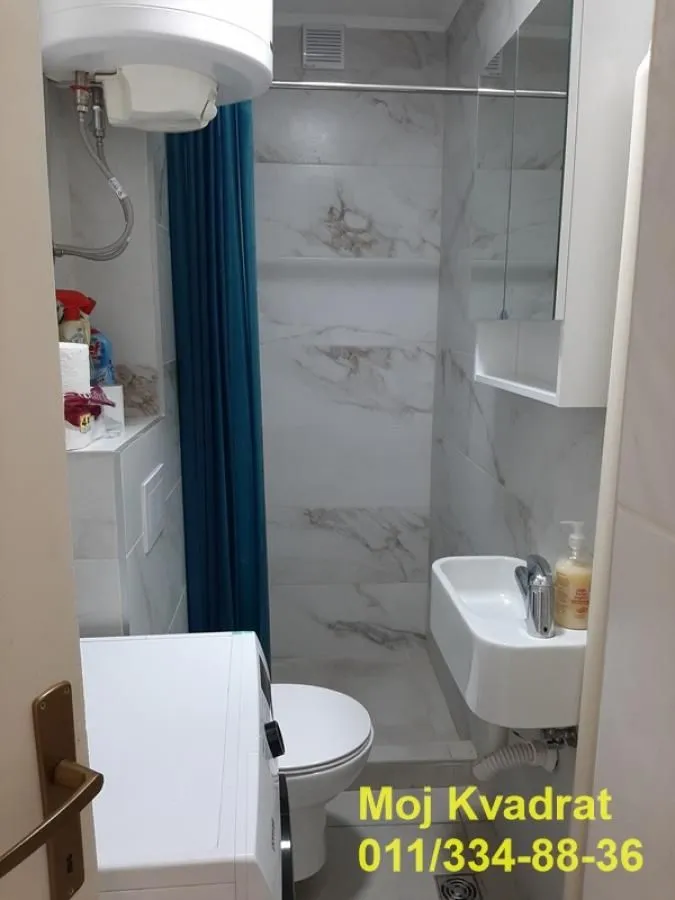 Smaller bathroom with a shower cabin, washbasin, and washing machine.