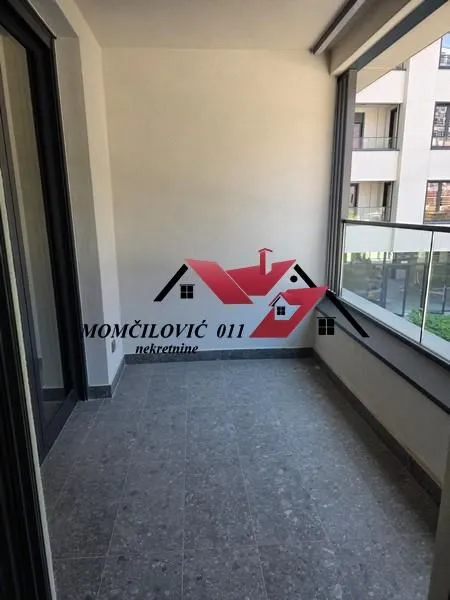 Natkrivena terasa sa keramičkim pločicama na podu i staklenom ogradom.
