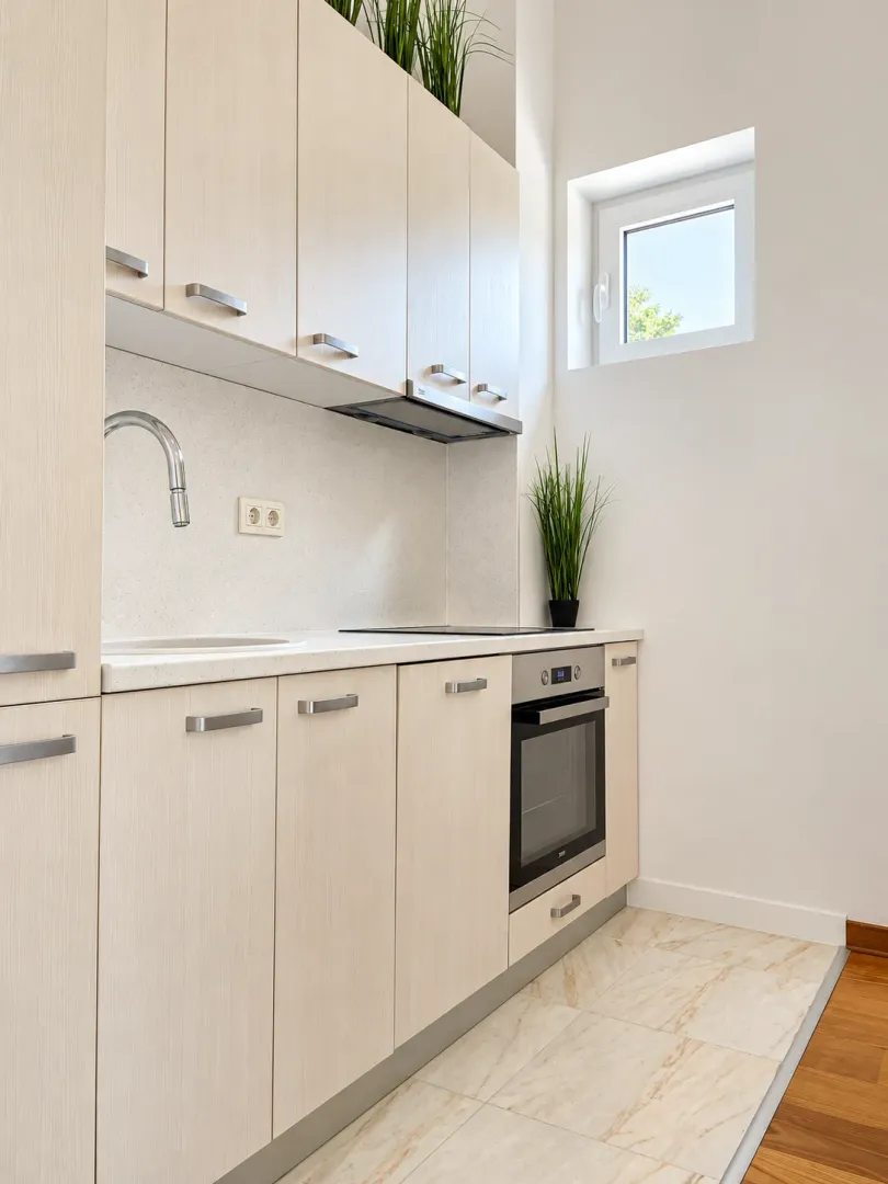 Modern kitchen with light wood cabinets and a built-in oven.