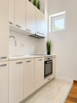 Modern kitchen with light wood cabinets and a built-in oven. - image 3