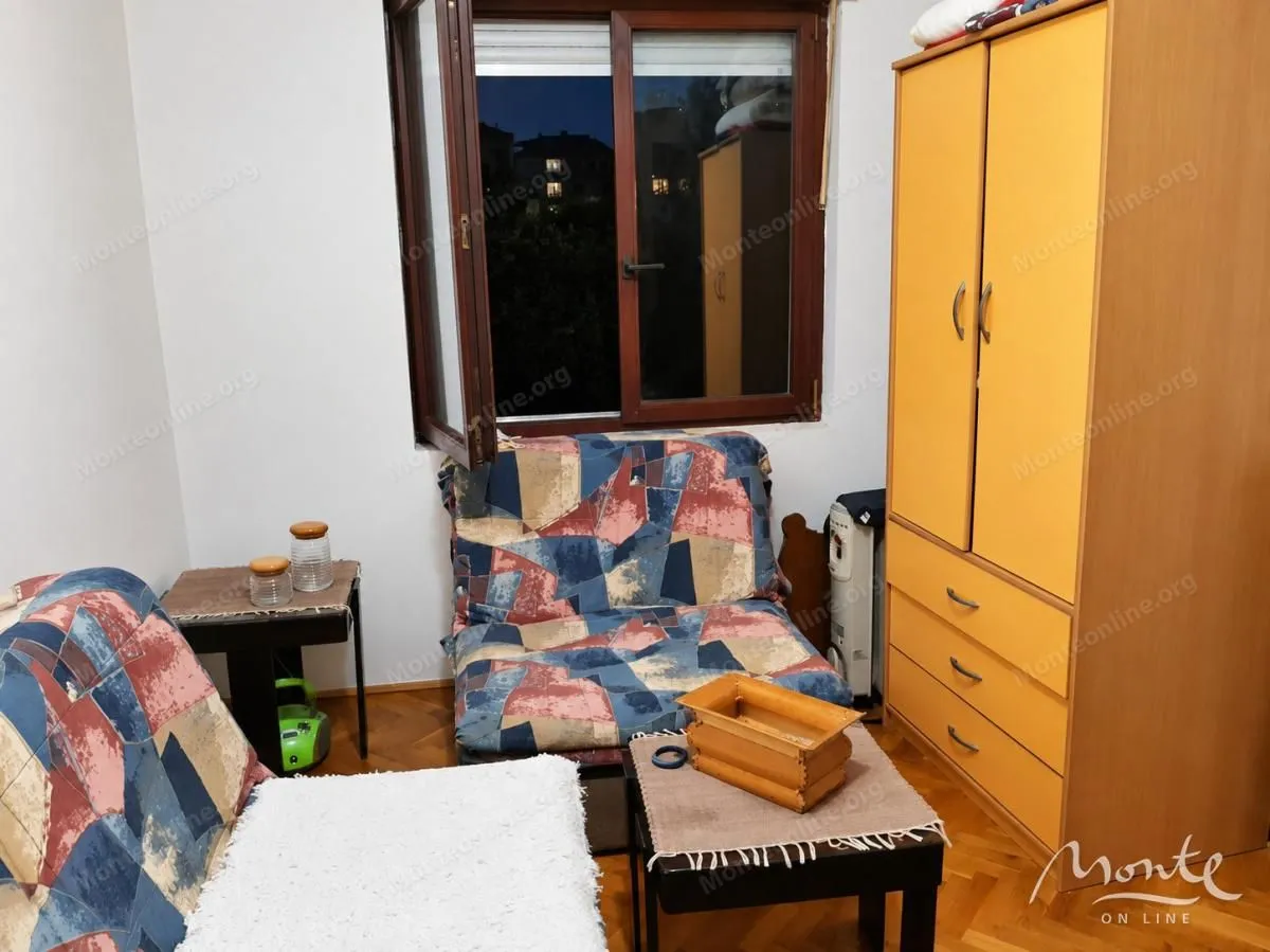Manja spavaća soba sa krevetom, garderoberom i prozorom.