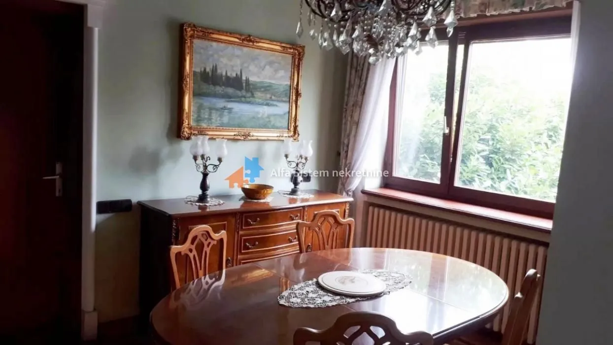 Dining room with a wooden table and chairs, a sideboard and a chandelier.