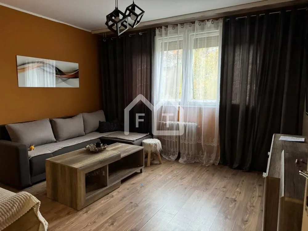 Living room with a sofa, coffee table, and a window with dark curtains.