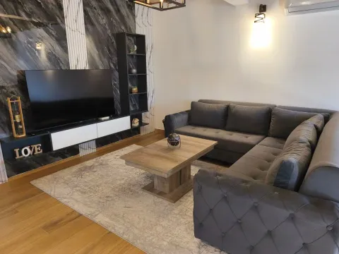 Living room with a sectional sofa, TV, and coffee table. - image 9