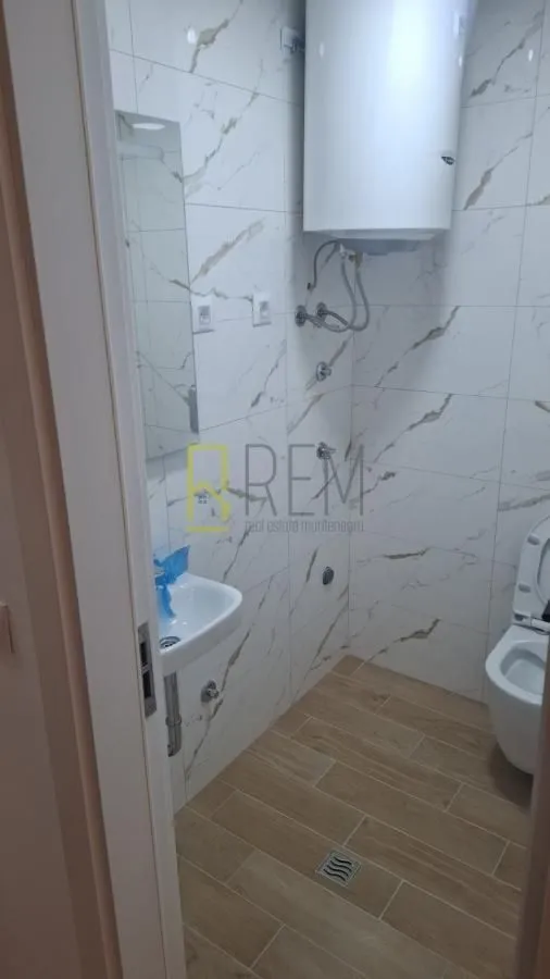 Manje kupatilo sa tuš kabinom u pločicama i sanitarijama.