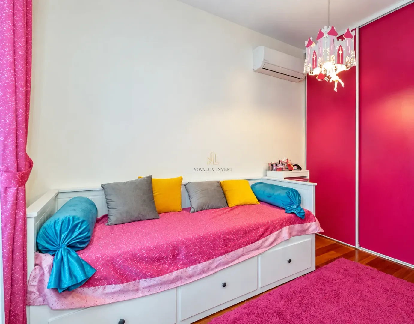 Dječija soba sa krevetom, roze detaljima i lusterom u obliku dvorca.