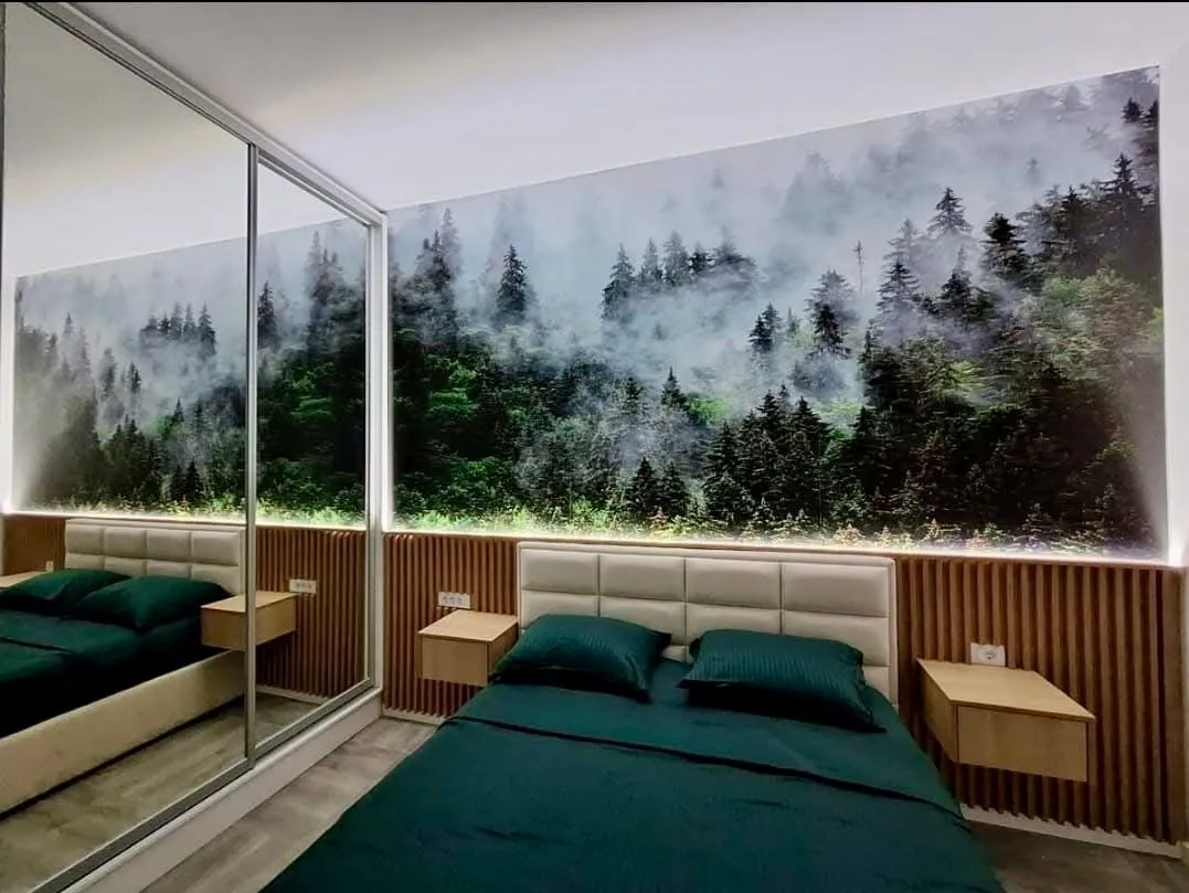 Modern bedroom with a double bed and forest motif wallpaper.