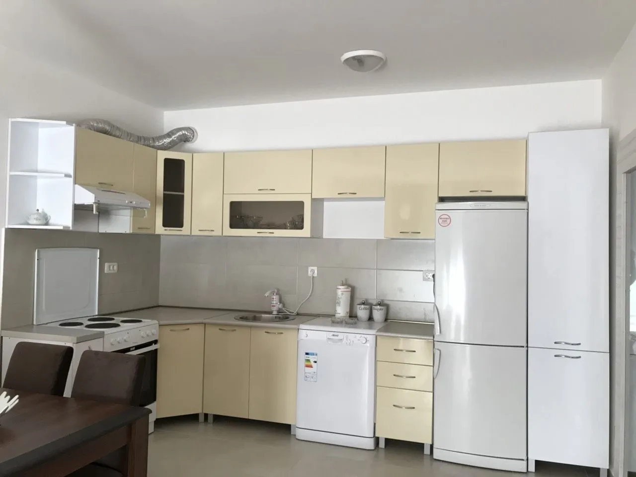 A furnished kitchen with beige and white cabinets and appliances.