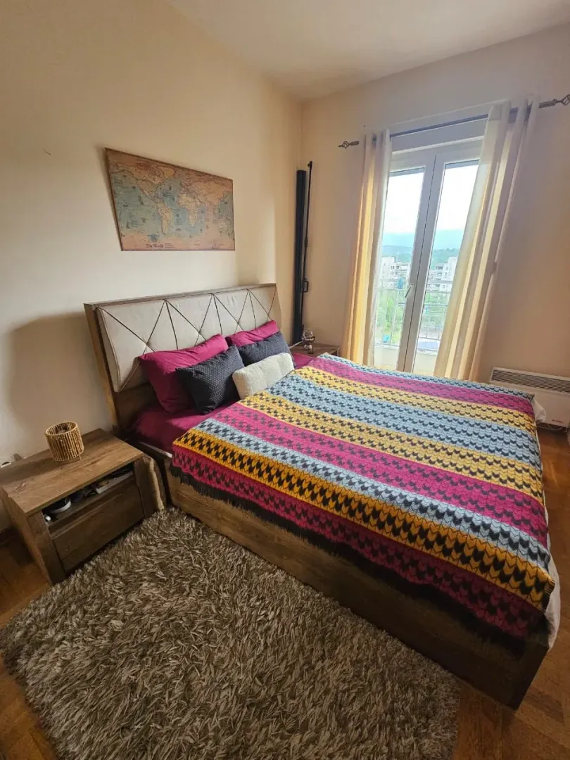 Spavaća soba sa bračnim krevetom, noćnim stočićima i prozorom koji gleda na okolinu.