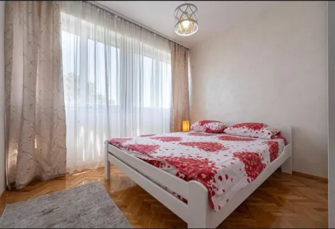 Bright bedroom with a double bed, parquet flooring, and a large window with curtains. - image 17