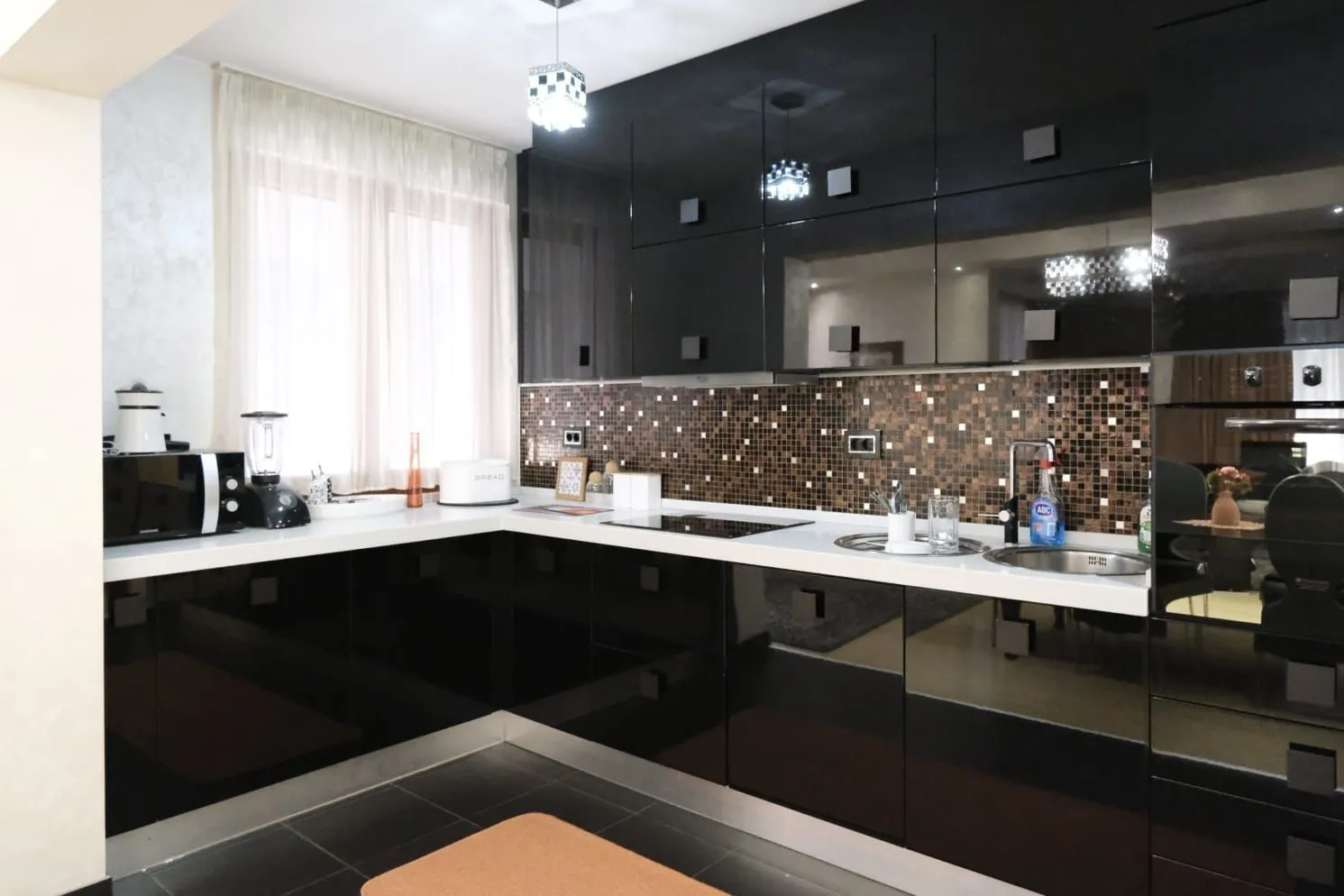 Modern kitchen with black glossy cabinets and a white countertop.