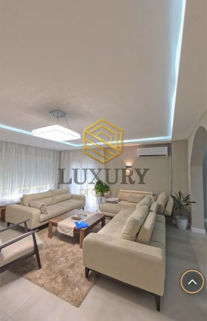 Spacious living room with seating furniture and modern lighting.