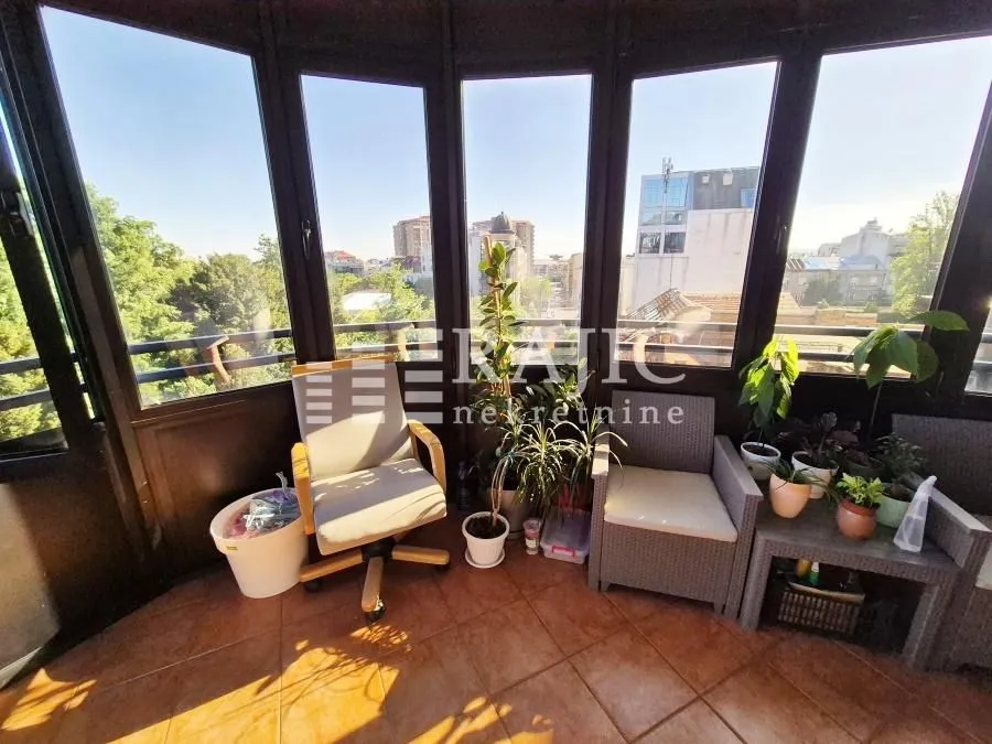 Enclosed terrace with seating furniture and a city view.