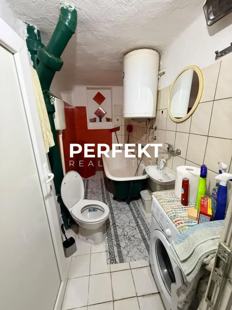 Manje kupatilo sa kadom, toaletom i mašinom za veš.