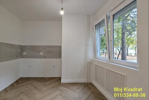 Prazna prostorija sa belim zidovima, parketom u obliku riblje kosti i prozorom sa pogledom na zelenilo. - image 3