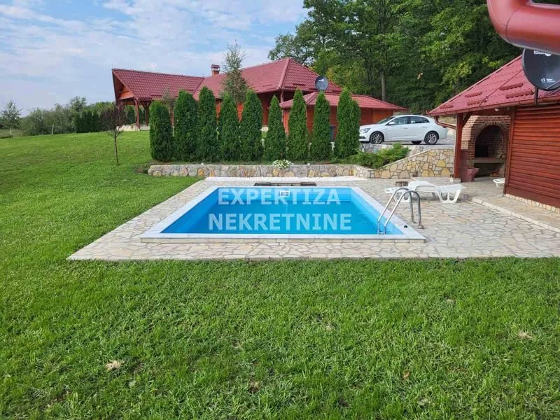 Dvorište kuće sa bazenom i zelenom površinom.