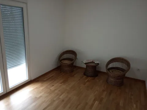 Prazna soba sa drvenim podom, balkonskim vratima i pletenim stolicama sa stočićem. - image 5