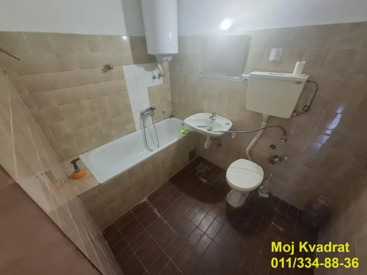 Manje opremljeno kupatilo sa kadom, umivaonikom i toaletom.