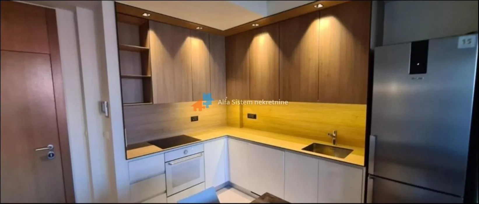 Kitchen equipped with white units, wooden upper cabinets and built-in appliances.