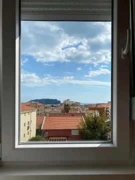 Pogled kroz prozor na naselje i more. - image 10