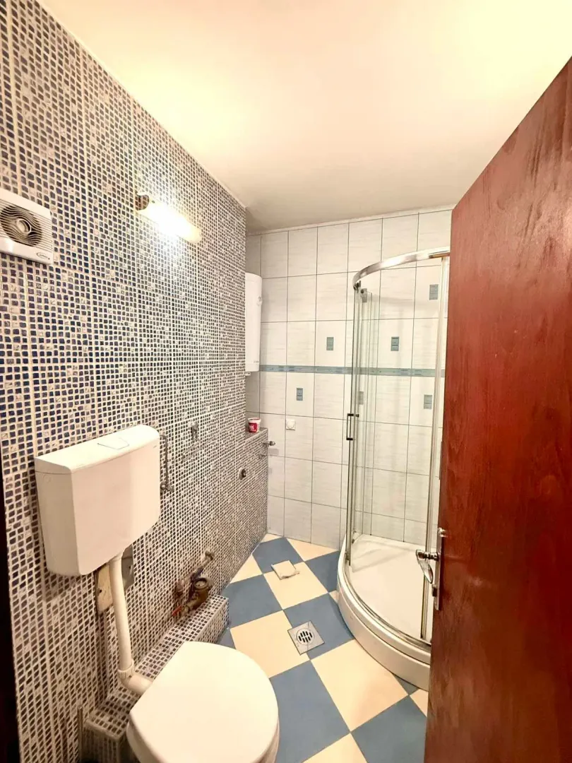 Manje kupatilo sa tuš kabinom, WC šoljom i pločicama u plavo-bijelim tonovima.