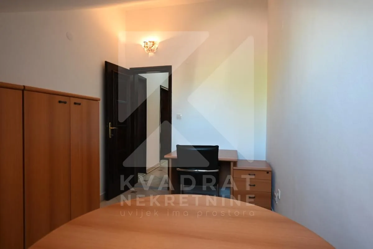 Small room with a desk, wardrobe, and an open door.