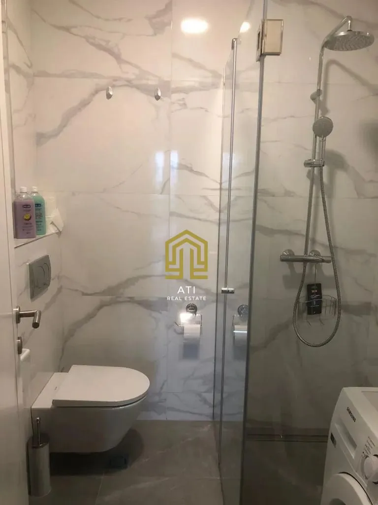 Modernly equipped bathroom with a walk-in shower and marble-style tiles.