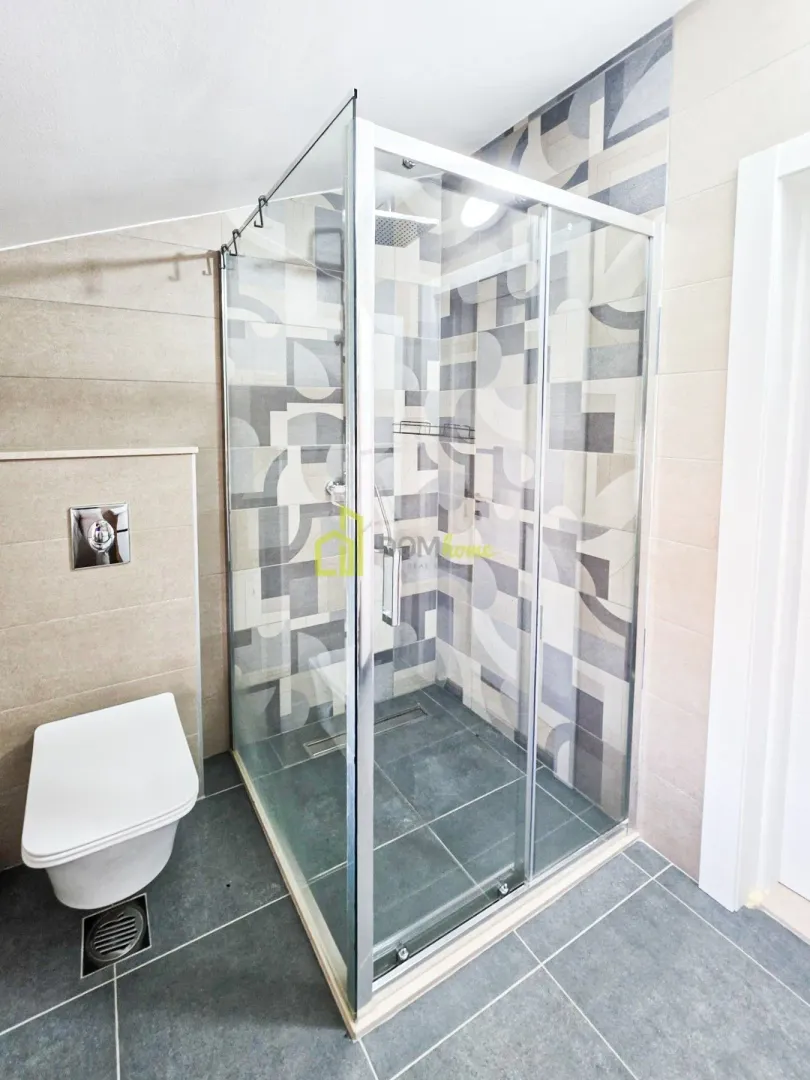 Modern bathroom with a walk-in shower and a wall-mounted toilet.