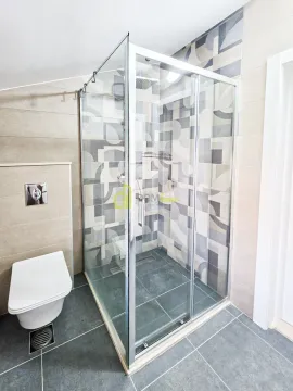 Modern bathroom with a walk-in shower and a wall-mounted toilet. - image 3