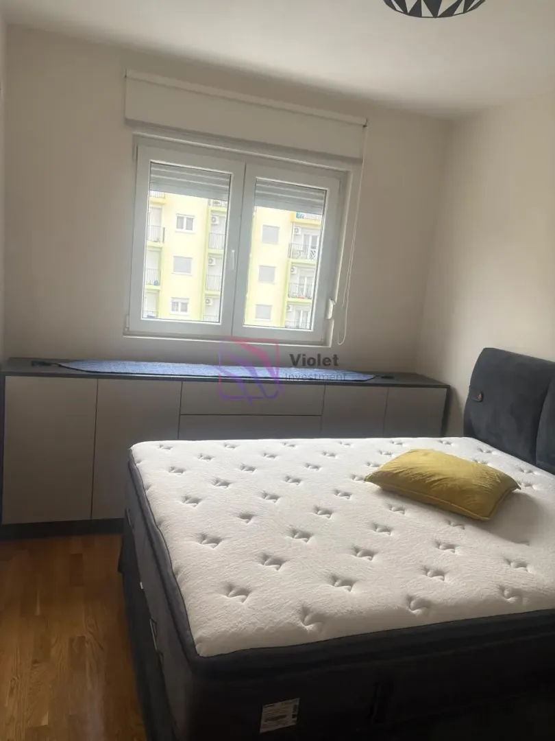 Bedroom with a double bed and a window overlooking neighboring buildings.