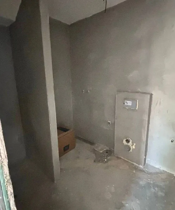 Room in grey phase of construction with installations.