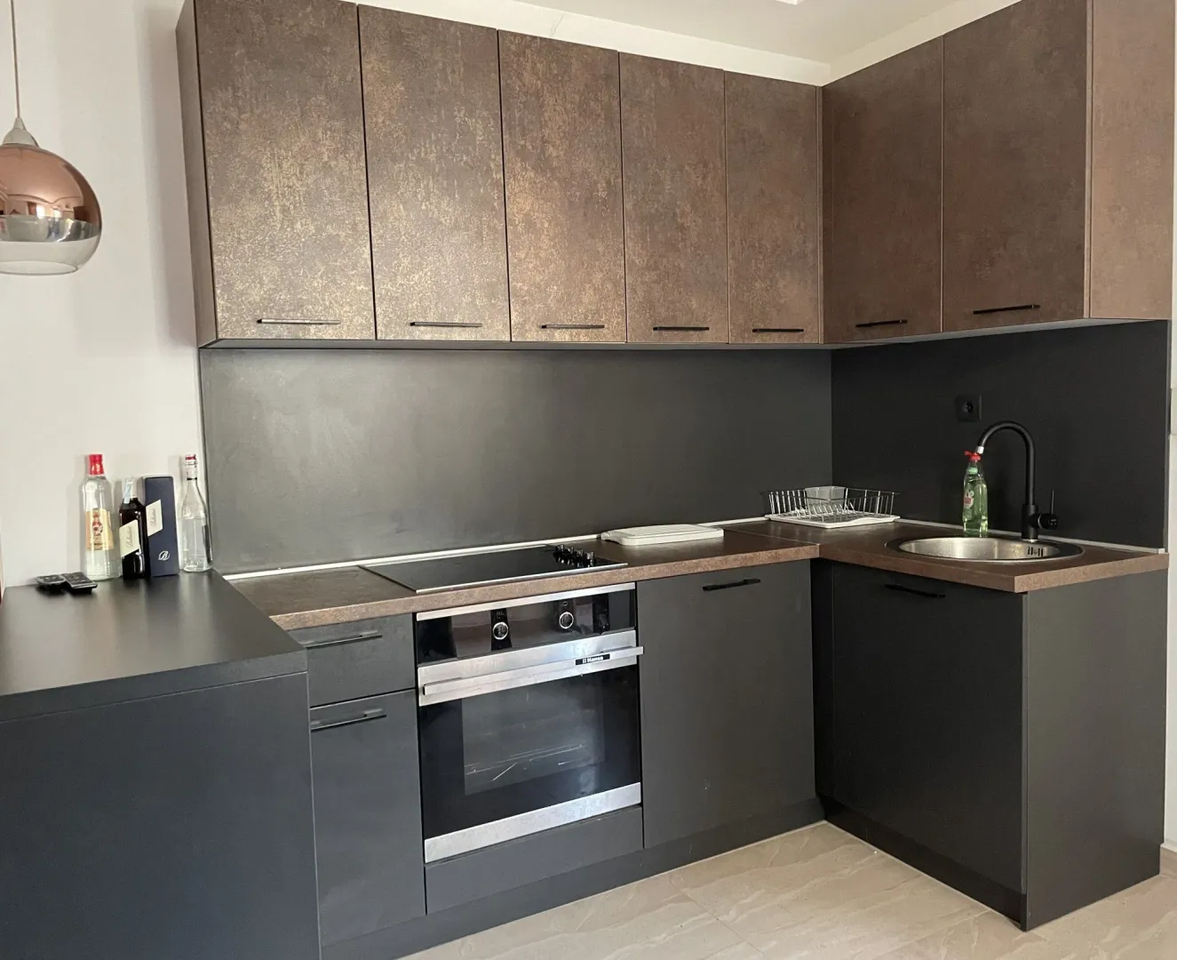 Modern kitchen with dark cabinetry and built-in oven.