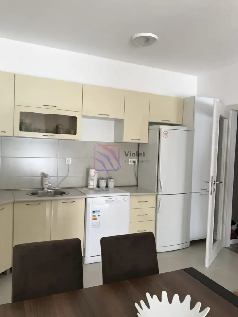 Kitchen equipped with light-coloured cabinets and white appliances.