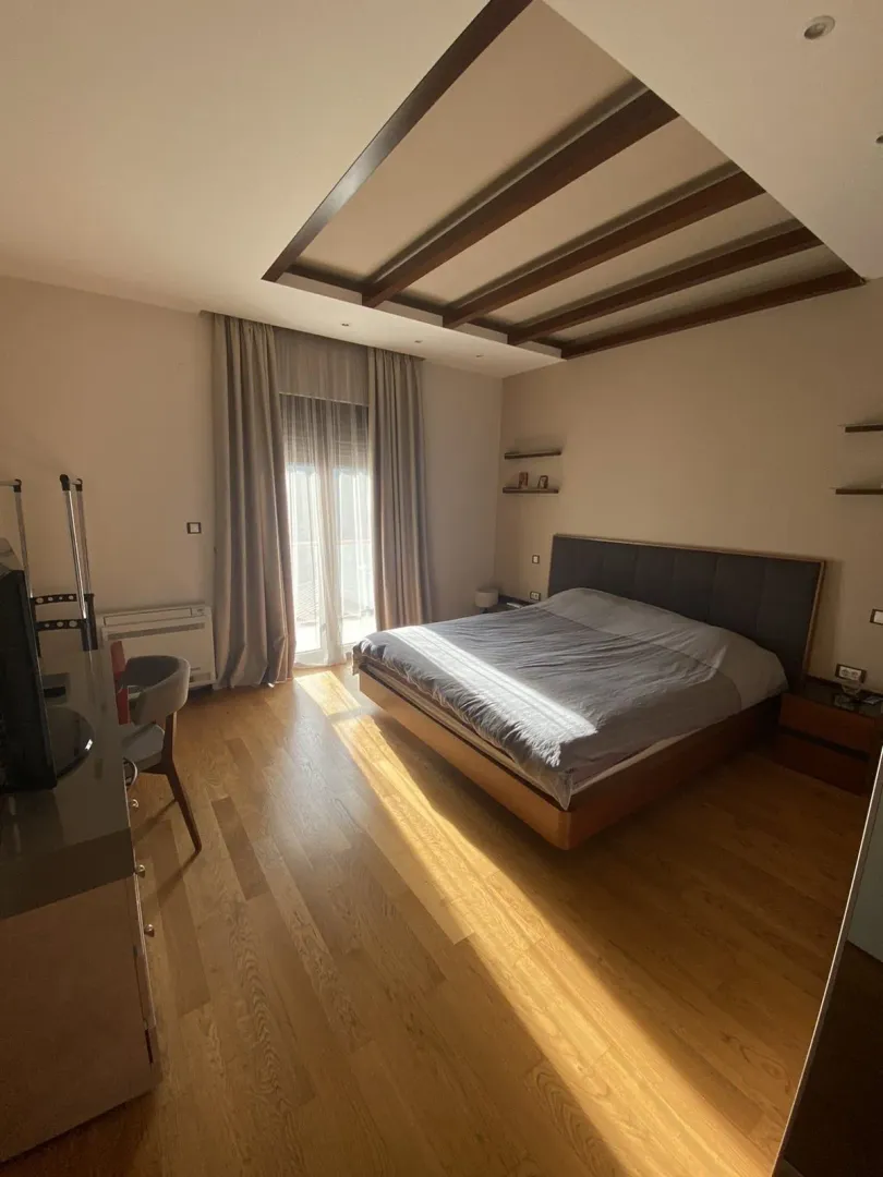 A bright bedroom with a large double bed and decorative ceiling beams.