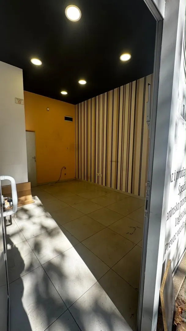 View through an open door into an empty room with tiled flooring and patterned wallpaper.