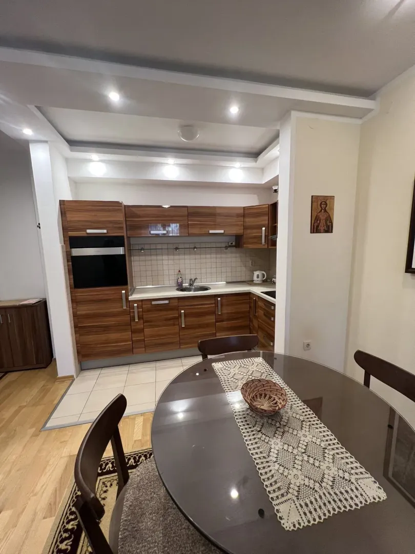 Dining table in front of a kitchen with wooden cabinets.