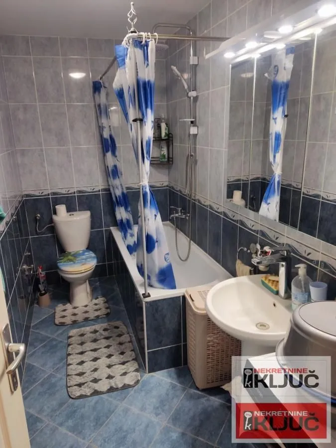 Kupatilo opremljeno kadom, umivaonikom, WC šoljom i plavim pločicama.