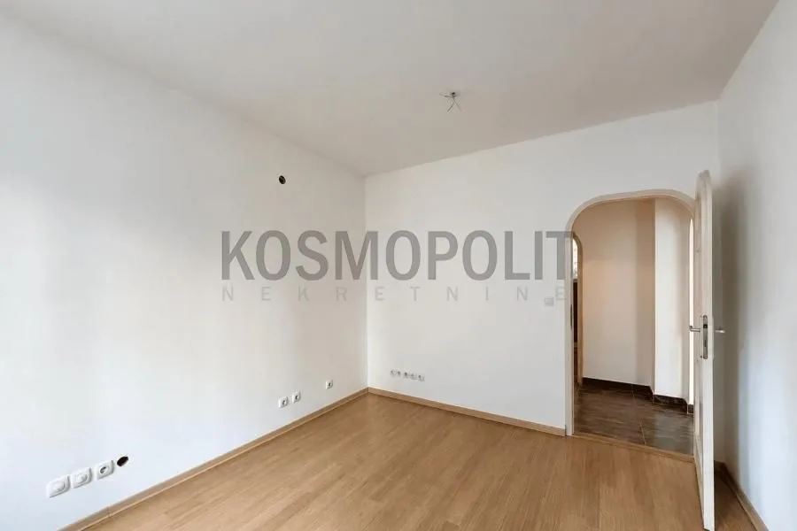 Empty room with laminate flooring and a door leading to the hallway.