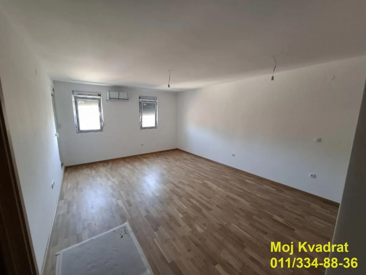 Prazna soba sa parketom i belim zidovima.
