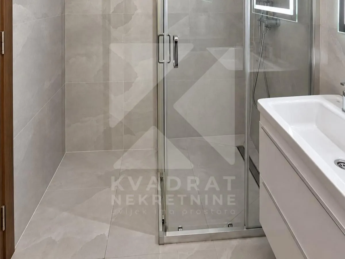 Moderne kupatilo sa tuš kabinom i umivaonikom sa ormarićem.