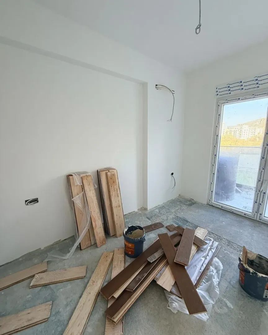 Empty room under construction with flooring material and tools.