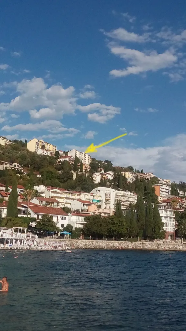 Pogled na višespratnice na obali mora sa ucrtanom žutom strelicom.