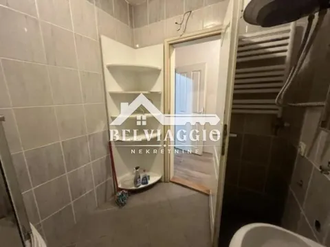 Manje kupatilo obloženo keramičkim pločicama sa ugrađenim policama i vratima koja vode u hodnik. - image 11