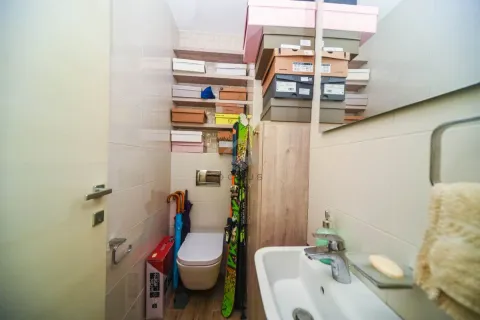 Bathroom equipped with a sink, toilet, and storage shelves. - image 3
