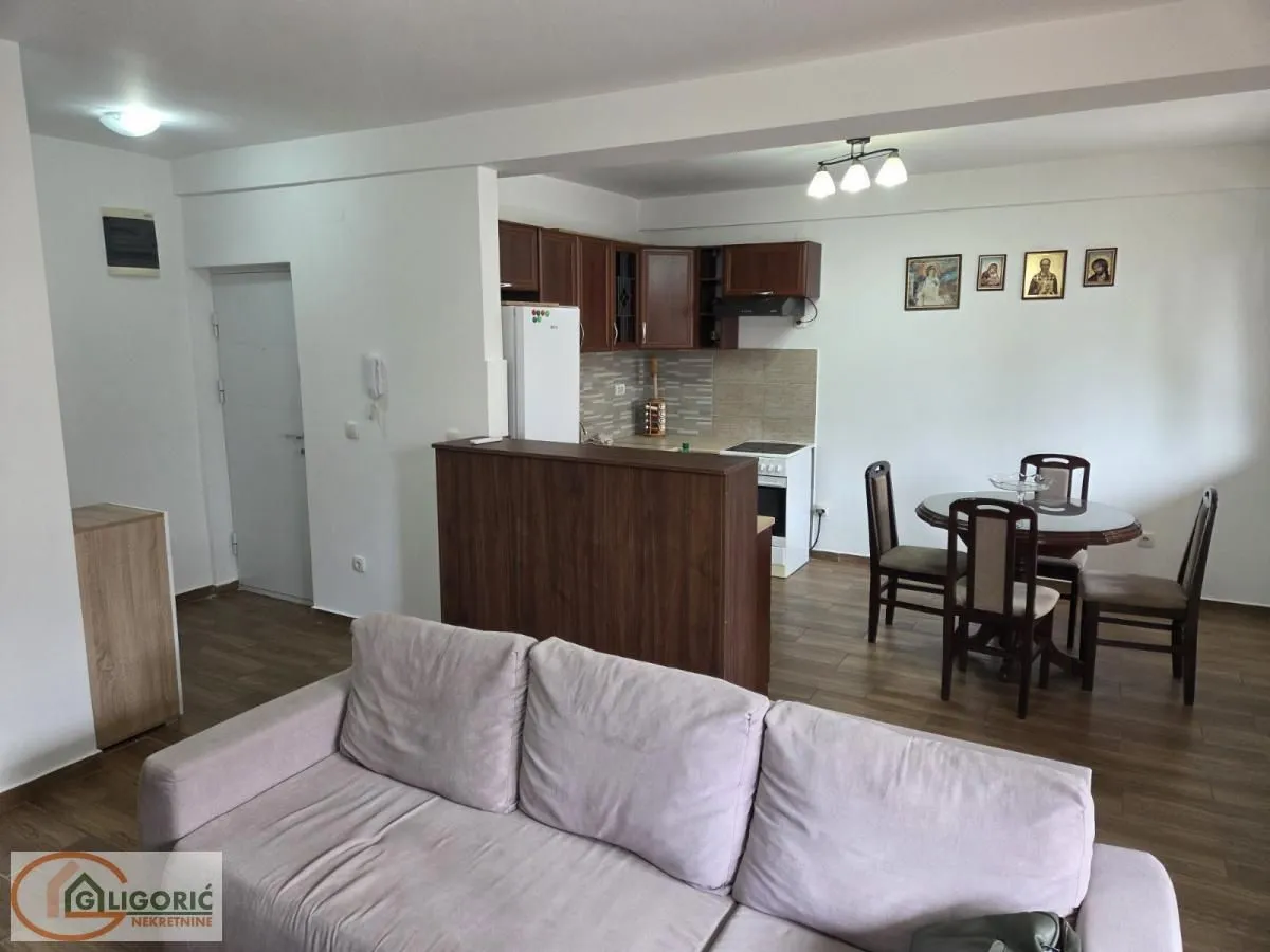 Living room with a sofa, dining area, and kitchen in the background.